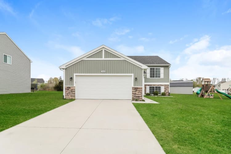 Portage apartments for rent - image - Charming suburban home with a spacious driveway, vibrant green lawn, and modern siding.