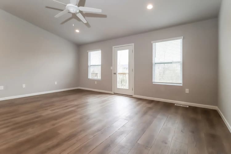 Portage apartments for rent - image - Bright and airy living space with modern wood flooring, large windows, and a ceiling fan, offering a perfect canvas for personal design.