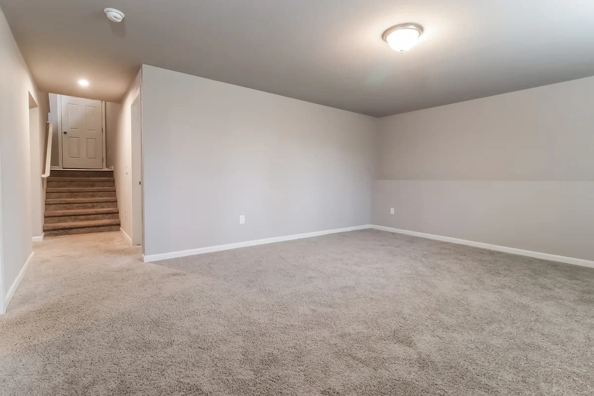 Portage apartments for rent - image - Spacious carpeted room with soft lighting, perfect for a cozy family space.