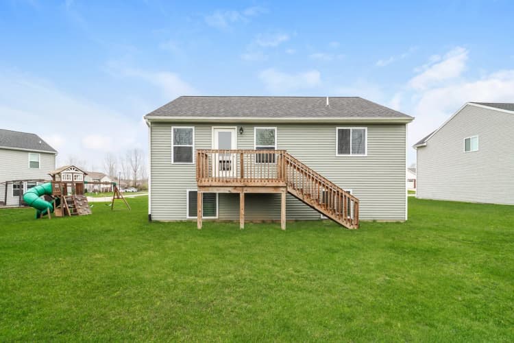 Portage apartments for rent - image - Charming suburban home with a wooden deck and lush green lawn, perfect for family living and outdoor play.