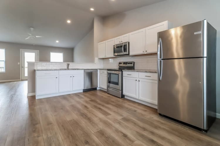 Portage apartments for rent - image - Contemporary open-plan kitchen with stainless steel appliances, sleek white cabinets, and warm hardwood flooring, offering a bright and spacious living area.
