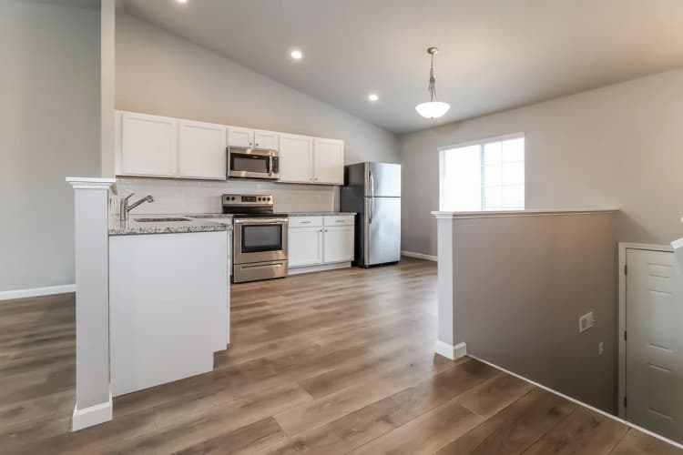 Portage apartments for rent - image - Contemporary kitchen featuring stainless steel appliances, sleek granite countertops, and elegant wooden flooring, illuminated by ample natural light.